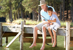 A retired man fishing with his grandson