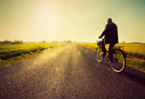 an old man riding his bike on the open road