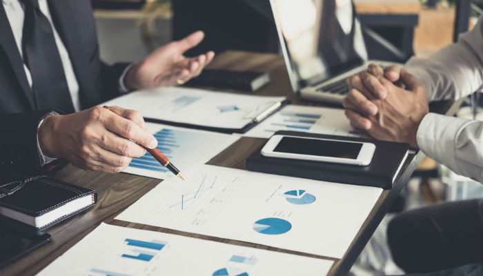 Business team meeting with investor colleagues discussing new plan financial graph data on office table with laptop and digital tablet