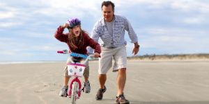 father helping daughter to ride a bike