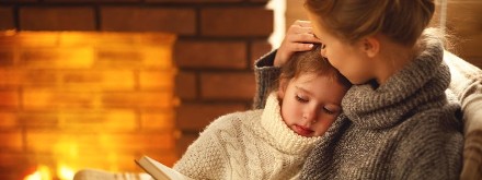mother and daughter reading book by the fire