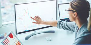 Photo of woman at computer screen looking at graphs