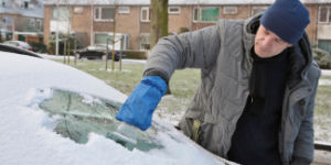 man deicing his car windscreen