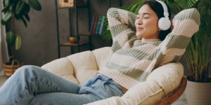 young woman in armchair listening on headphone