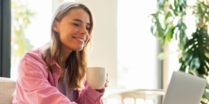 smiling woman having coffee at her laptop