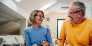 Elderly senior couple sitting at table while working on a blueprints of their new home