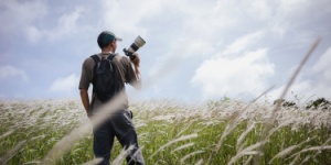 Cameraman standing holding camera in the middle of a meadow