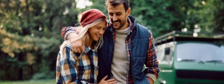 Happy couple walking embraced while camping in the forest