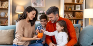 happy family father mother and two children with orange piggy bank
