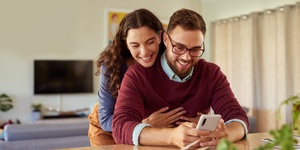 young couple at home hugging on mobile phone