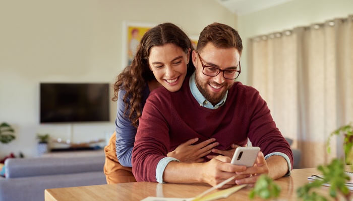 young couple at home hugging on mobile phone