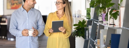 Couple of happy young office friends walking in co-working space