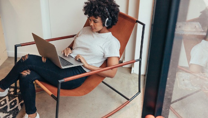 Young woman sitting on relaxing chair using laptop