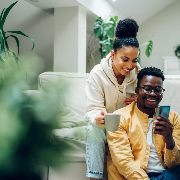 african couple at home on phone and having coffee